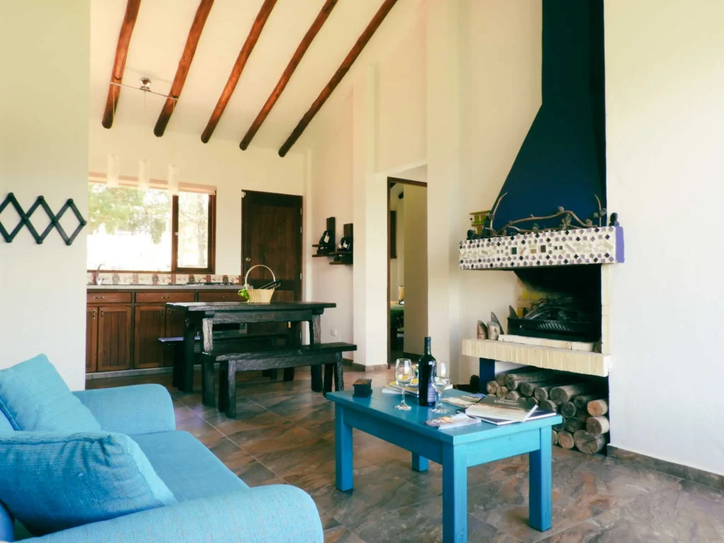 Acogedora sala de estar y comedor de Casa Zuetana en Zipaquirá, con sofá azul, chimenea y vigas de madera expuestas.