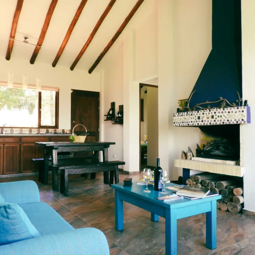 Acogedora sala de estar y comedor de Casa Zuetana en Zipaquirá, con sofá azul, chimenea y vigas de madera expuestas.