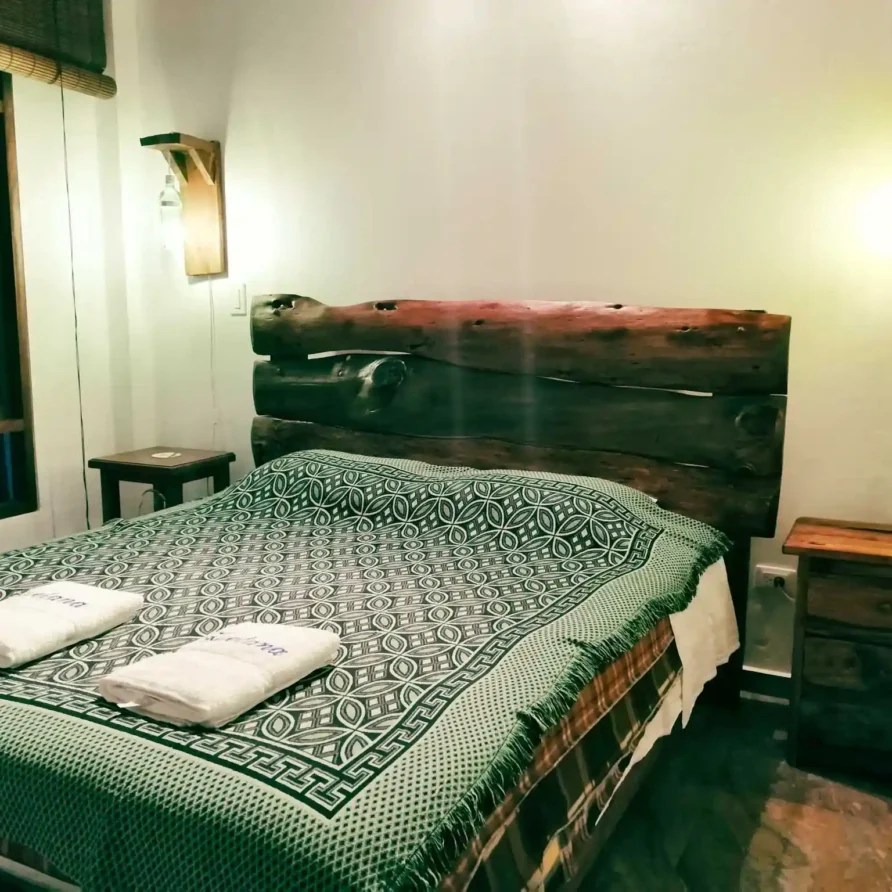 Habitación rústica en Casa Zuetana, Zipaquirá con cama doble, cabecero de madera y lámparas artesanales.