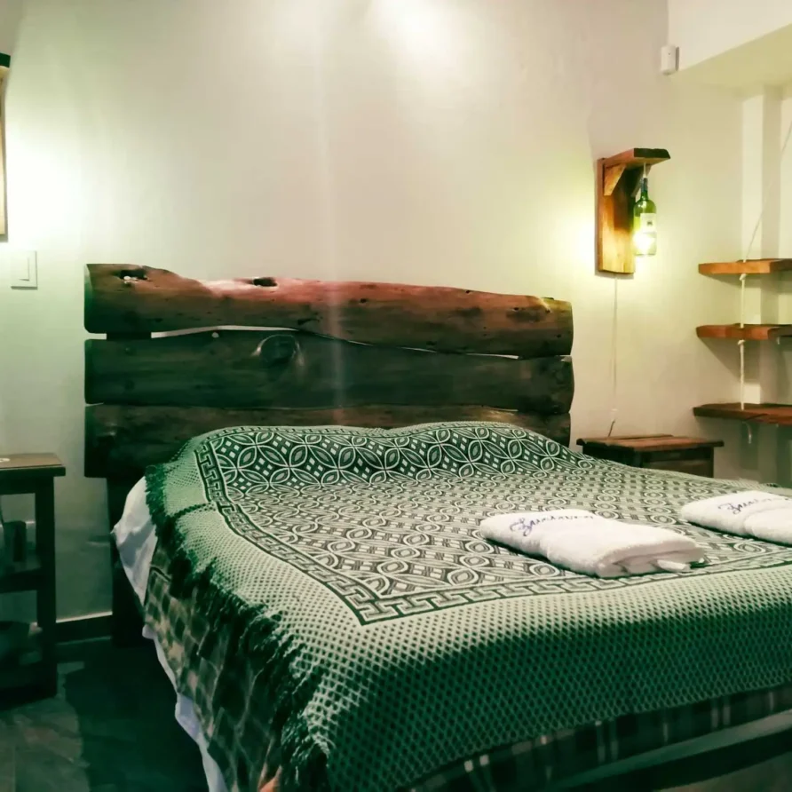 Dormitorio acogedor de alquiler vacacional en Zipaquirá, con decoración de madera y manta verde.