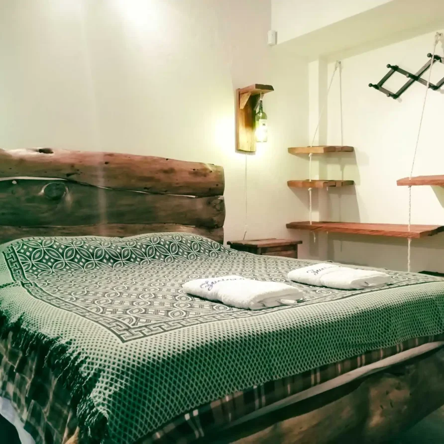 Habitación rústica en Casa Zuetana, Zipaquirá con cama doble, cabecero de madera y lámparas artesanales.