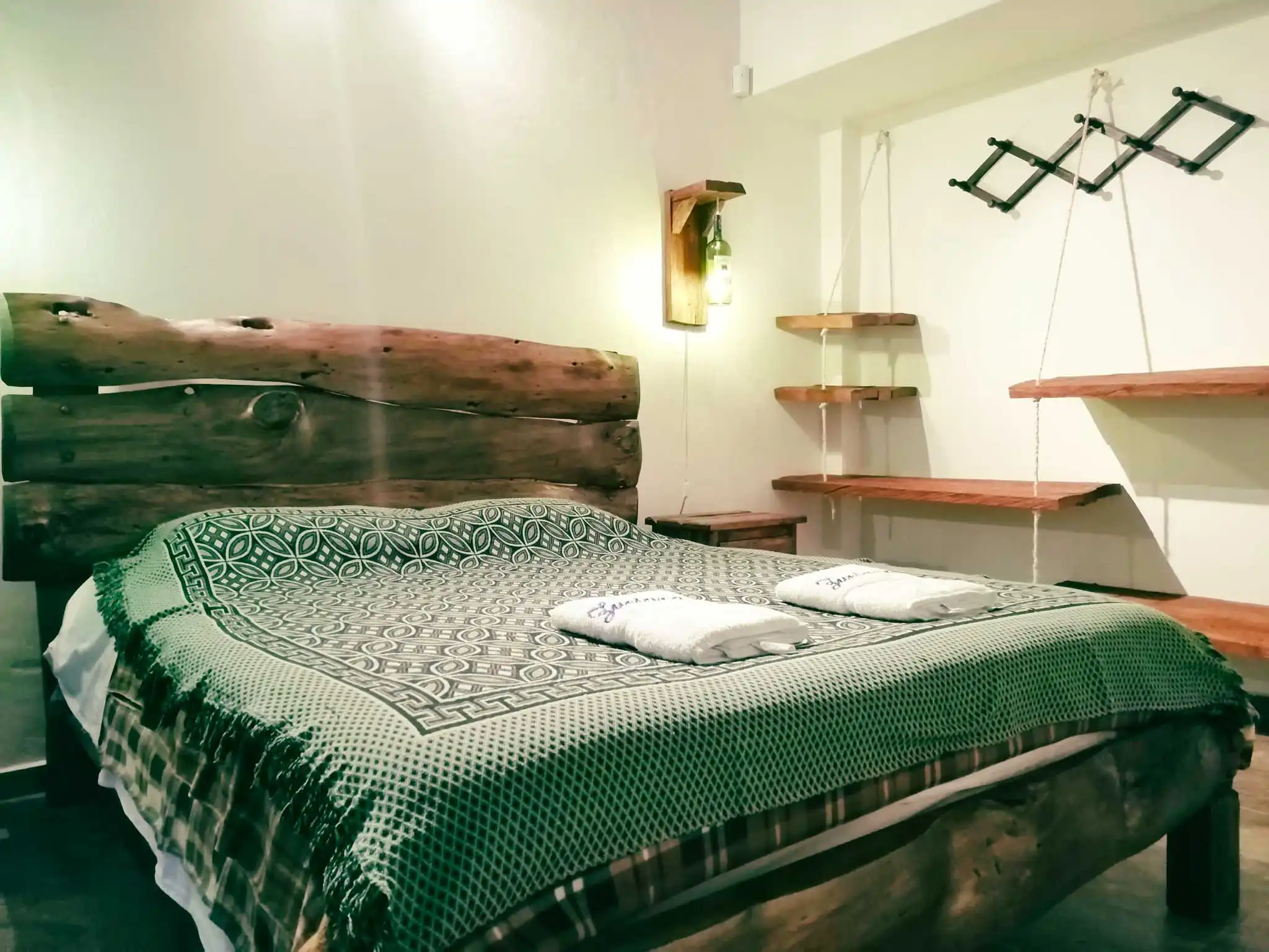 Habitación rústica en Casa Zuetana, Zipaquirá con cama doble, cabecero de madera y lámparas artesanales.