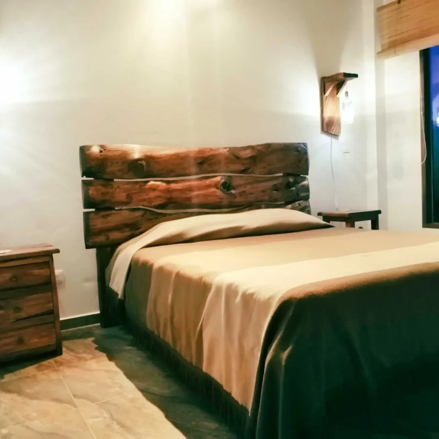 Dormitorio rústico en Casa Zuetana, Zipaquirá, con cabecero de madera natural y detalles acogedores.