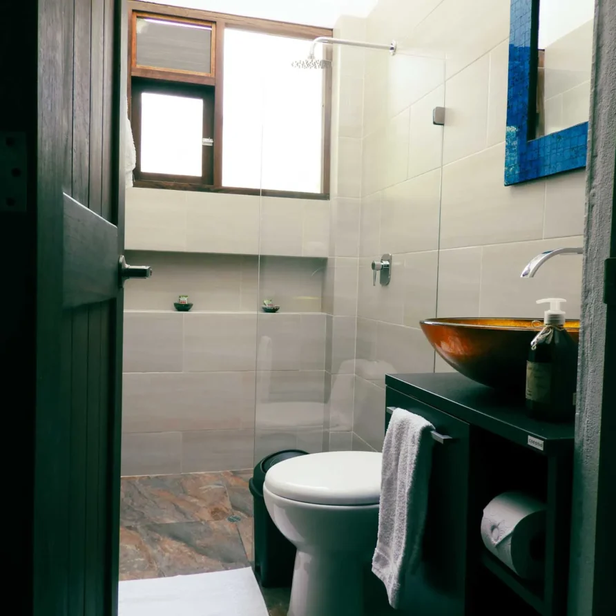 Interior de baño bien equipado en casa de alquiler vacacional en Zipaquira, featuring ducha, inodoro y espejo.