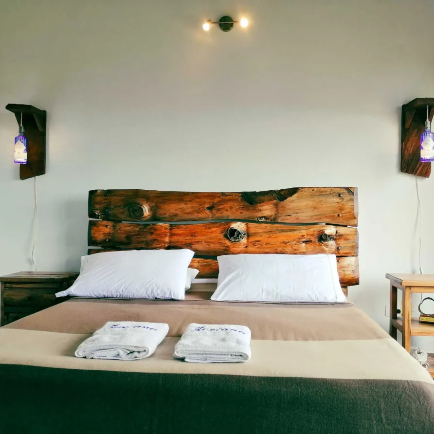 Dormitorio rústico en Casa Zuetana Zipaquirá con cabecero de madera y lámparas artesanales.