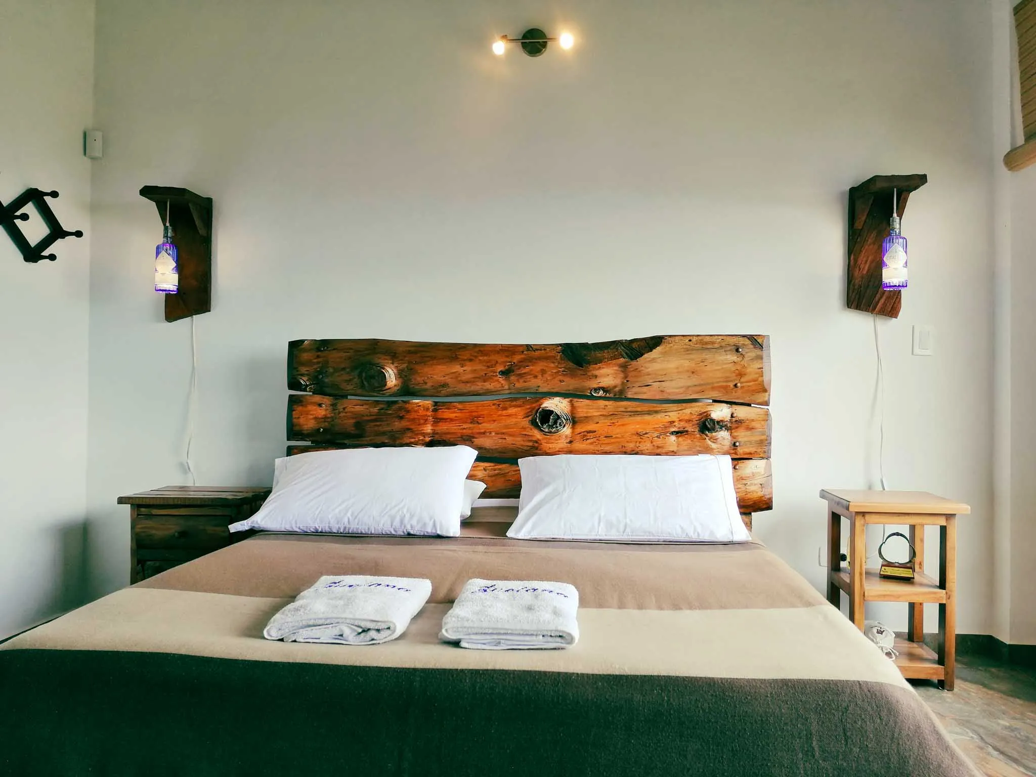 Dormitorio rústico en Casa Zuetana Zipaquirá con cabecero de madera y lámparas artesanales.