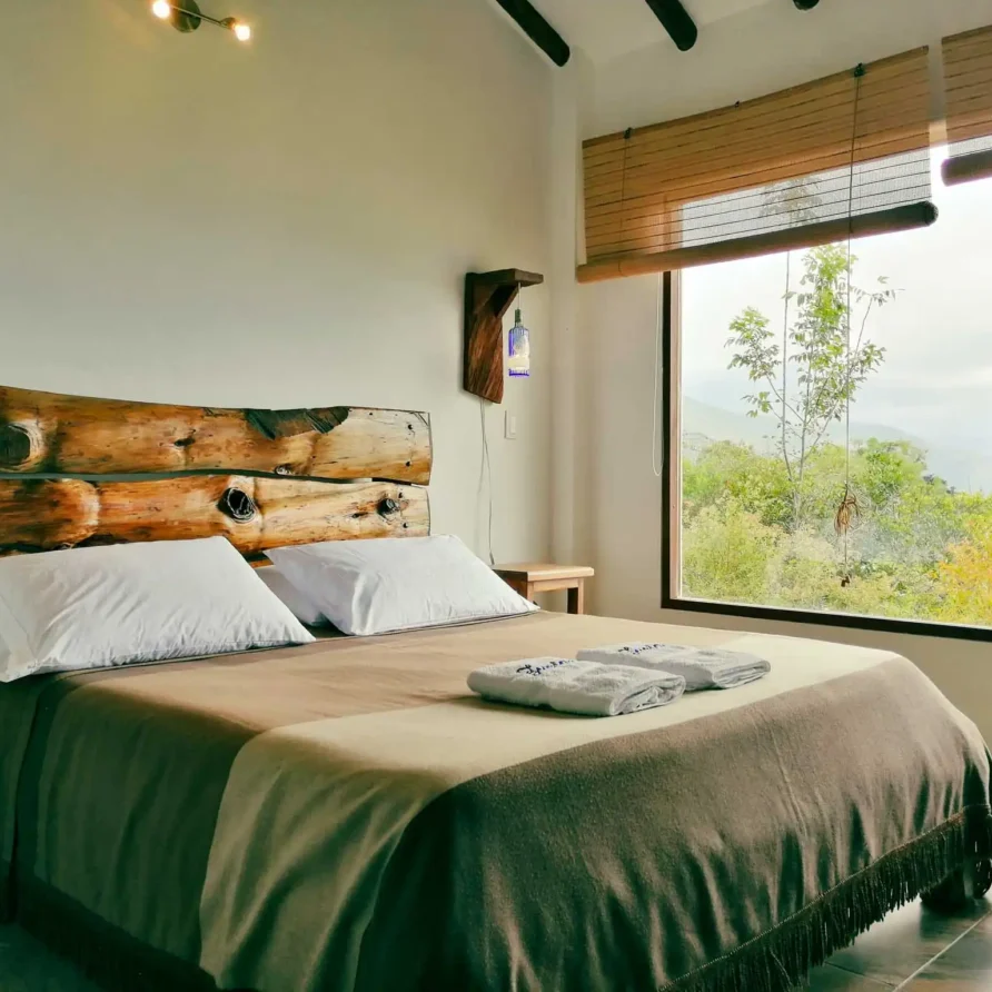 Dormitorio acogedor de alquiler vacacional en Zipaquira, con cama doble y decoración de madera, vista a la naturaleza.