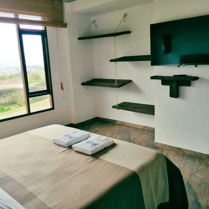 Hermosa habitación en Casa Zuetana cerca de Zipaquira, con cama confortable, detalles rústicos y panorámica verde.
