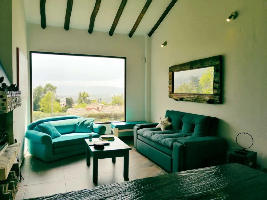 Sala de estar acogedora en Casa Zuetana, Zipaquirá, con sofás, mesa de centro y gran ventanal con vistas.
