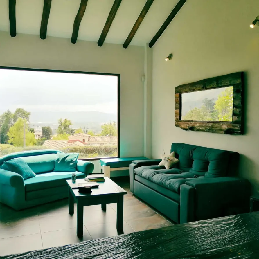 Sala de estar acogedora en Casa Zuetana, Zipaquirá, con sofás, mesa de centro y gran ventanal con vistas.