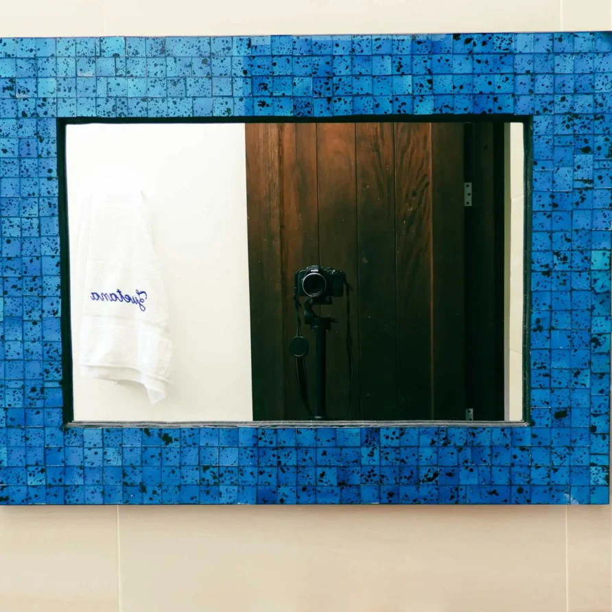 Espejo rectangular con marco de mosaico azul cobalto, ideal para un baño en casa vacacional.