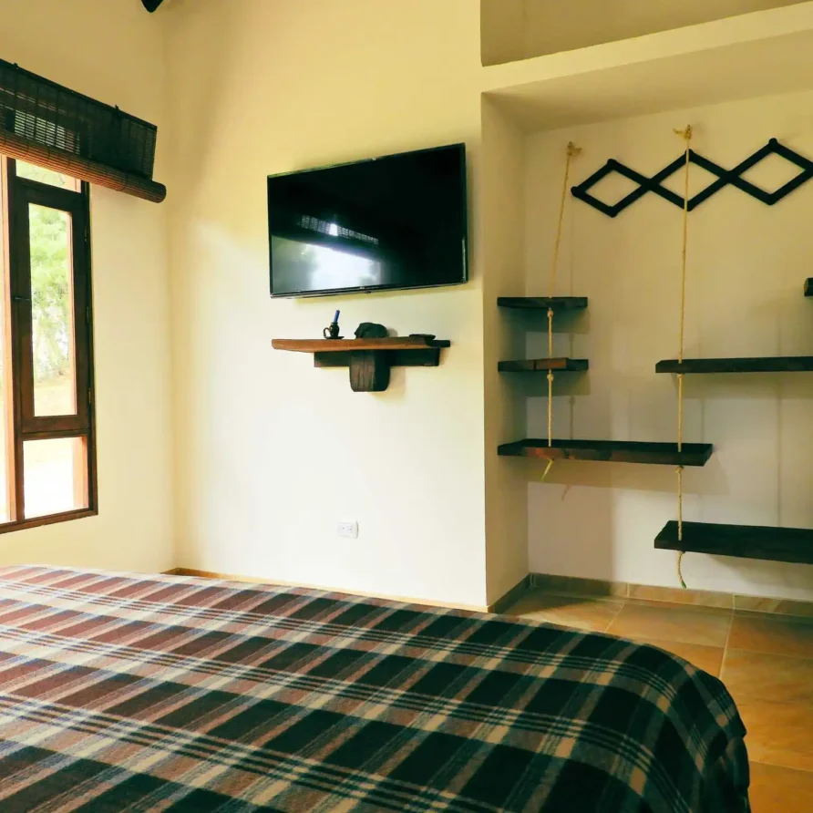 Acogedora habitación de alquiler vacacional en Zipaquirá con manta a cuadros, televisión y persianas de bambú.