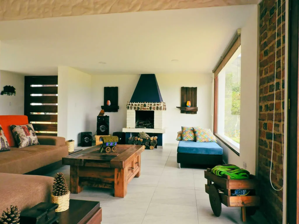 Interior de Casa Hichatana: salón con chimenea de piedra, muebles de madera y diseño campestre en Zipaquirá.
