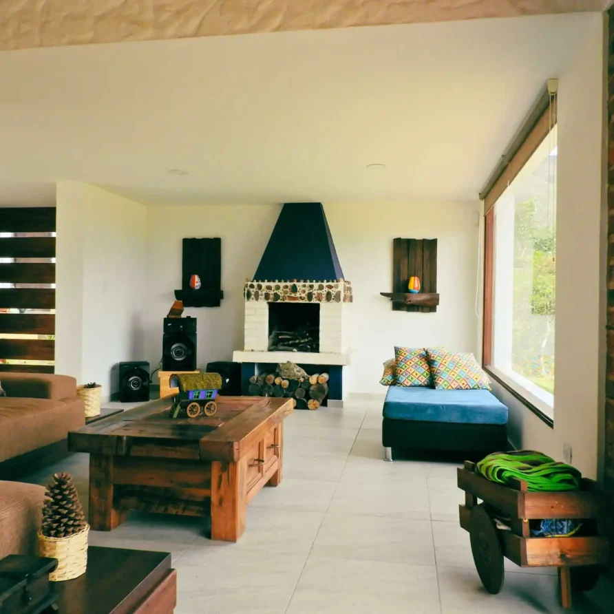 Interior de Casa Hichatana: salón con chimenea de piedra, muebles de madera y diseño campestre en Zipaquirá.