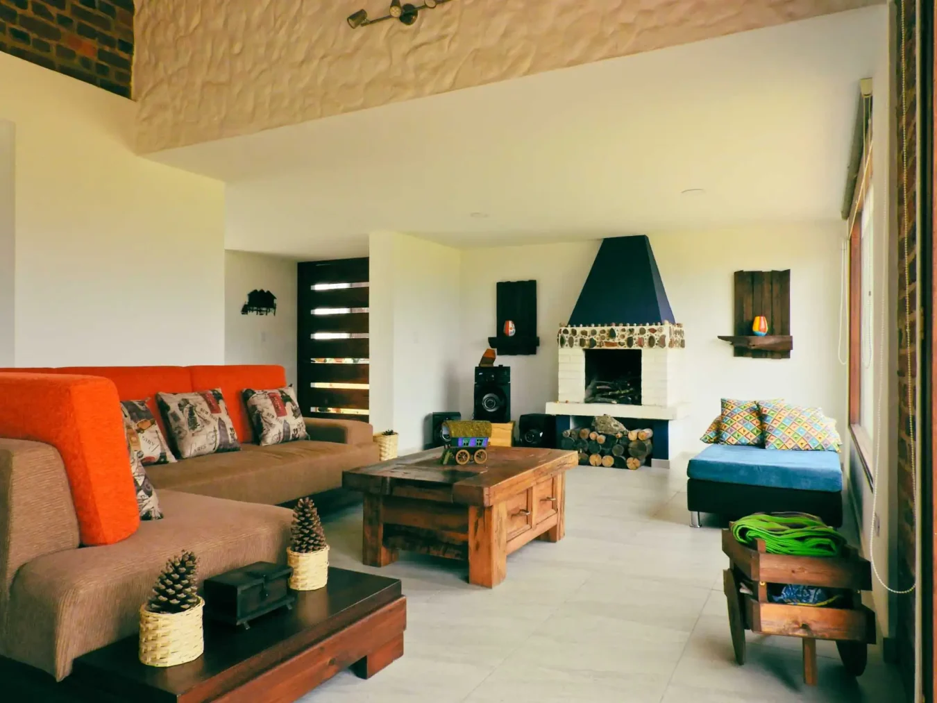 Sala de estar rústica de Casa Hichatana en Zipaquirá con sofá naranja, chimenea y mobiliario de madera.