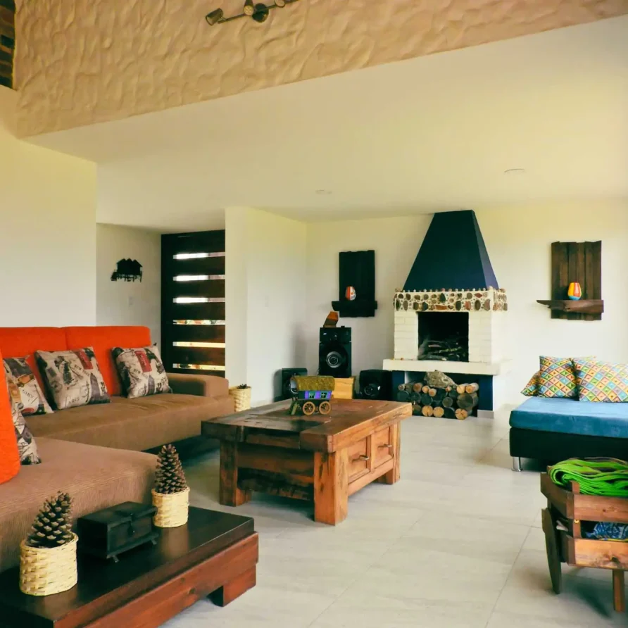 Sala de estar rústica de Casa Hichatana en Zipaquirá con sofá naranja, chimenea y mobiliario de madera.