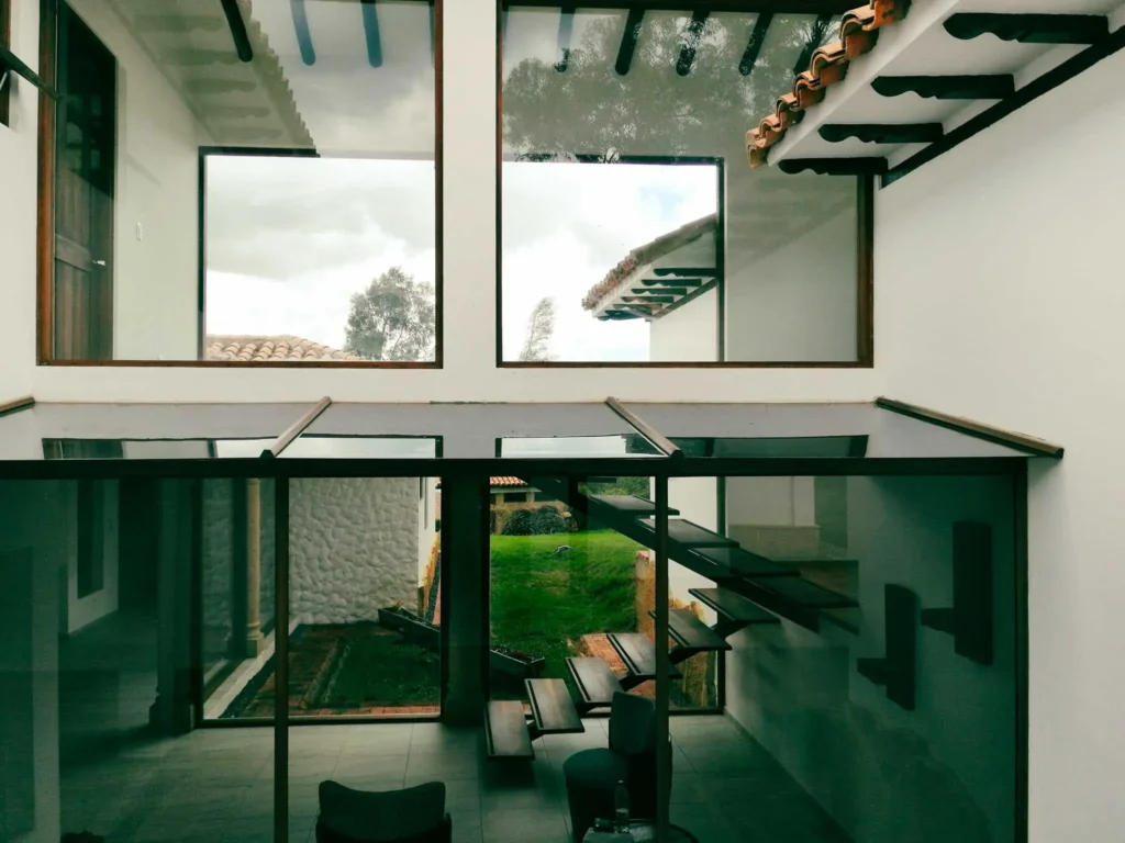 Interior moderno de Casa Hichatana en Zipaquirá con escaleras flotantes, grandes ventanales y vistas al jardín.
