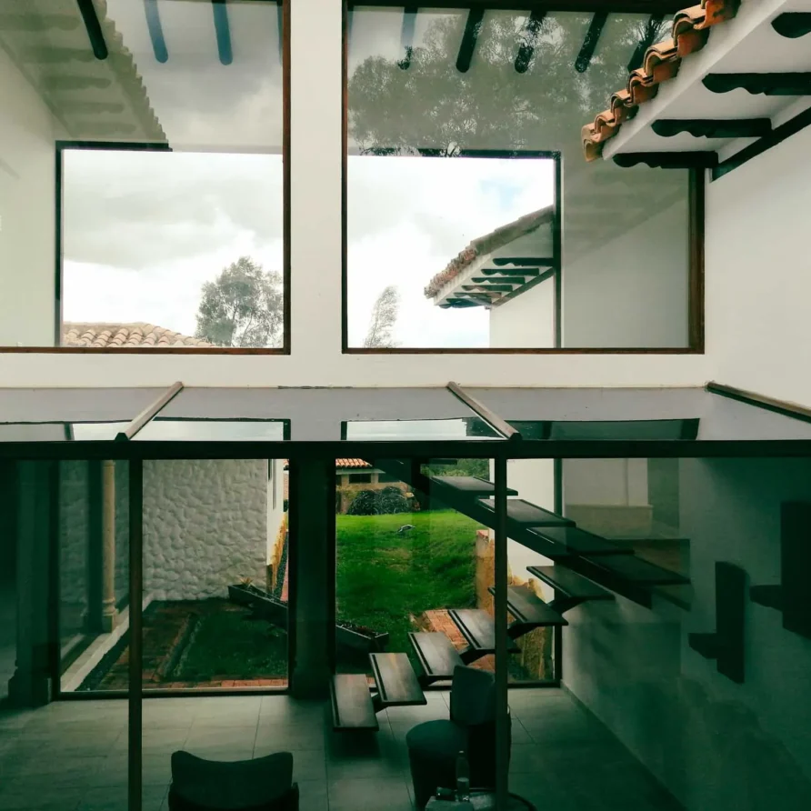 Interior moderno de Casa Hichatana en Zipaquirá con escaleras flotantes, grandes ventanales y vistas al jardín.