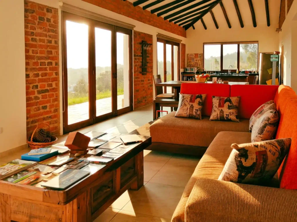 Interior acogedor de casa de alquiler en Zipaquirá con grandes ventanales, techo con vigas y mobiliario rústico de madera.