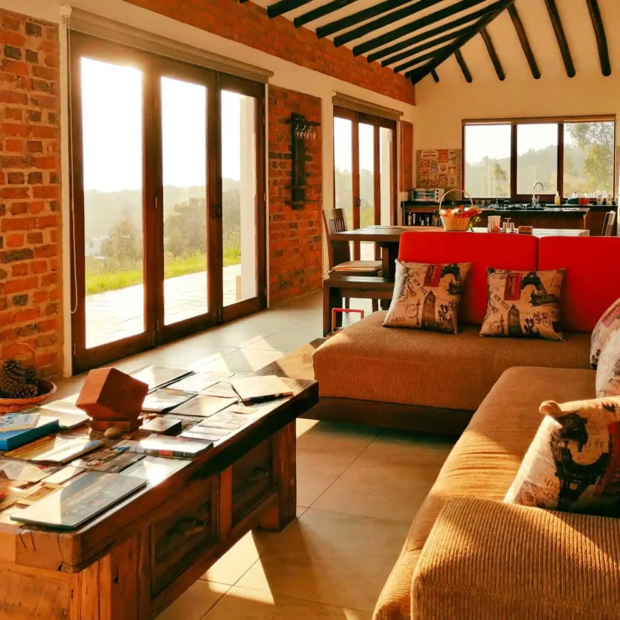 Interior acogedor de casa de alquiler en Zipaquirá con grandes ventanales, techo con vigas y mobiliario rústico de madera.