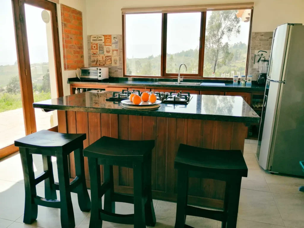 Amplia cocina de alquiler vacacional en Zipaquirá con isla de granito, fogones y grandes ventanales.