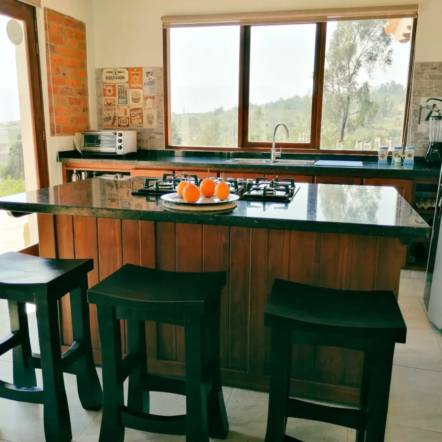 Amplia cocina de alquiler vacacional en Zipaquirá con isla de granito, fogones y grandes ventanales.