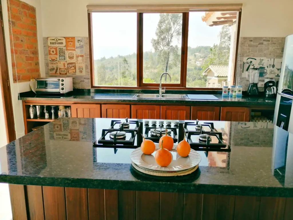 Cocina moderna y luminosa de Casa Hichatana en Zipaquirá, con isla de granito, estufa y vistas panorámicas.