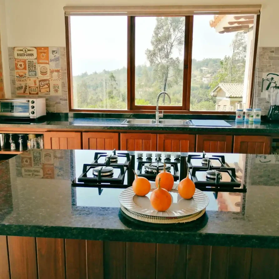 Cocina moderna y luminosa de Casa Hichatana en Zipaquirá, con isla de granito, estufa y vistas panorámicas.