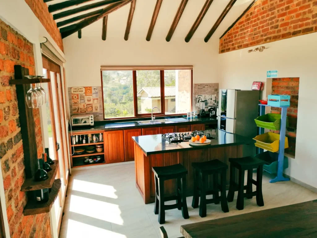 Cocina moderna y rústica de Casa Hichatana en Zipaquirá, con isla, vista al paisaje y paredes de ladrillo visto.