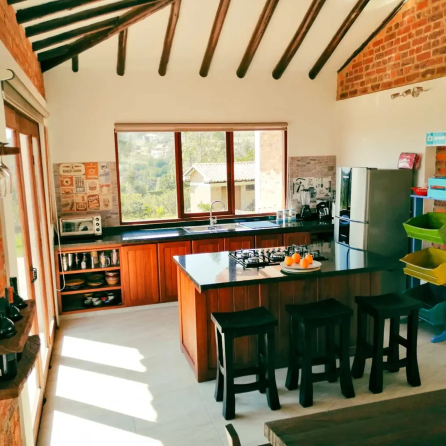 Cocina moderna y rústica de Casa Hichatana en Zipaquirá, con isla, vista al paisaje y paredes de ladrillo visto.