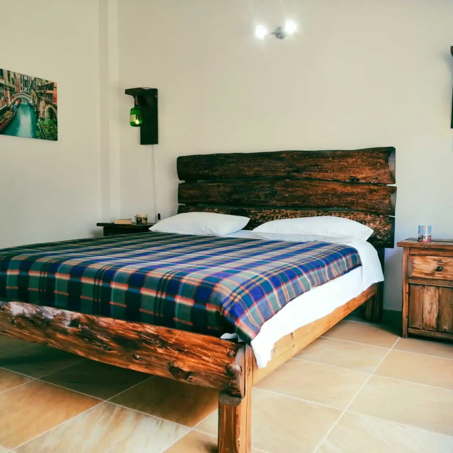 Cama rústica de madera con manta a cuadros en un dormitorio de Casa Hichatana, ideal para alquiler vacacional en Zipaquirá.