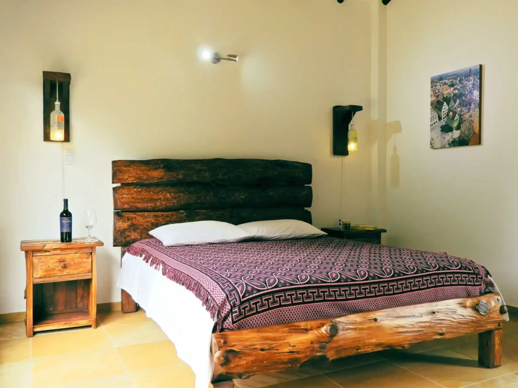 Habitación rústica en Casa Hichatana Zipaquira con cama de madera, manta decorativa y lámparas de botella.