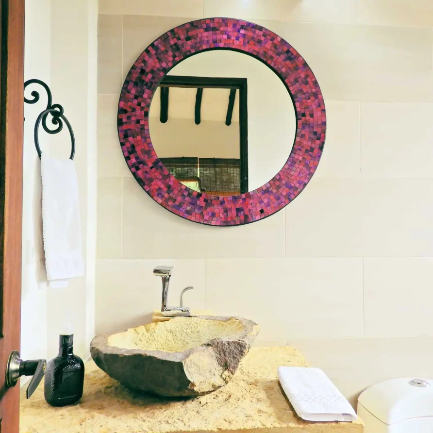 Baño de diseño en Casa Hichatana, Zipaquira: lavabo de piedra, espejo con marco mosaico y toallero de forja.