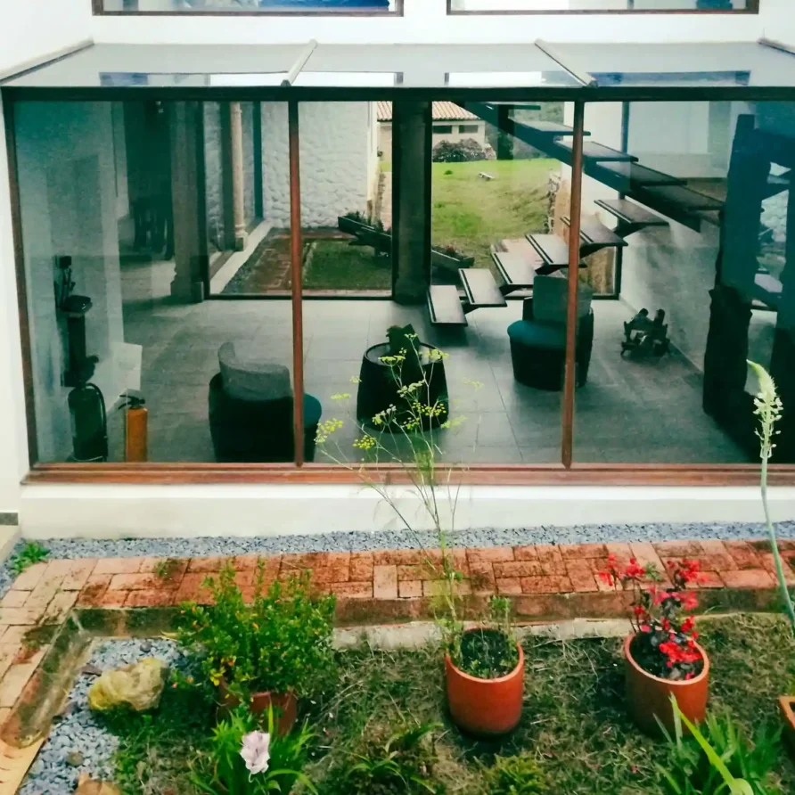 Exterior de Casa Hichatana en Zipaquirá con grandes ventanales que muestran un interior moderno y un jardín.