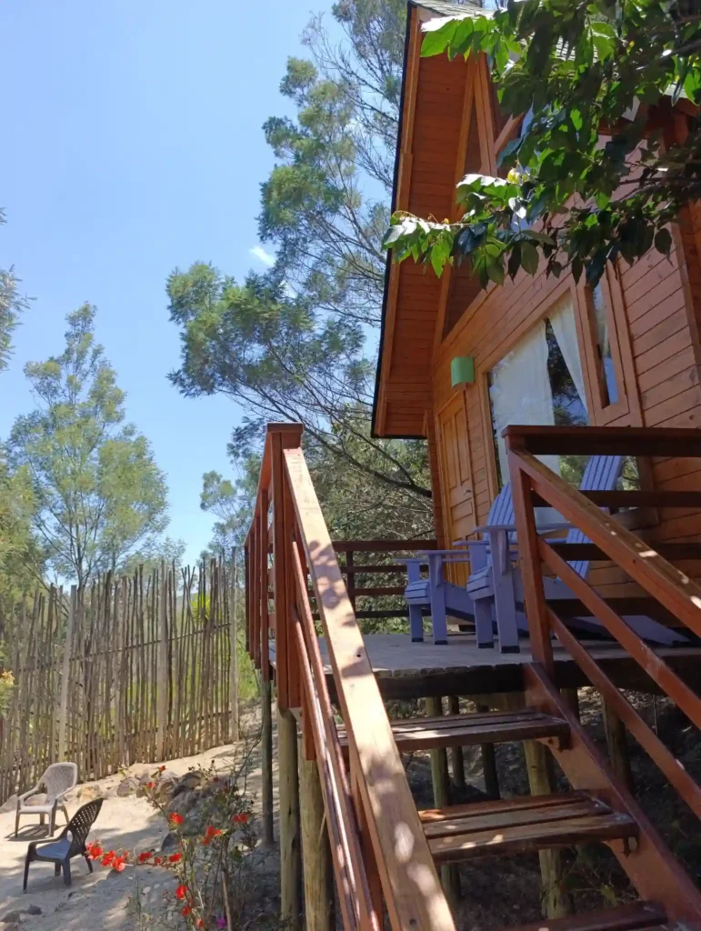 Vista exterior de la Cabaña el Ensueño, una acogedora cabaña con escaleras y porche entre árboles frondosos en Monquirá. hotel Hichatana y Zuetana
