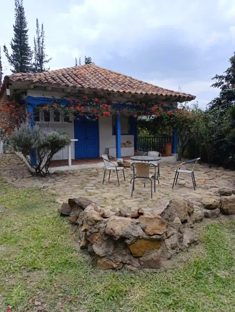 Vista de la Cabaña El Oteo, Villa de Leyva, fachada azul y blanca, tejado colonial, fogón de piedra.