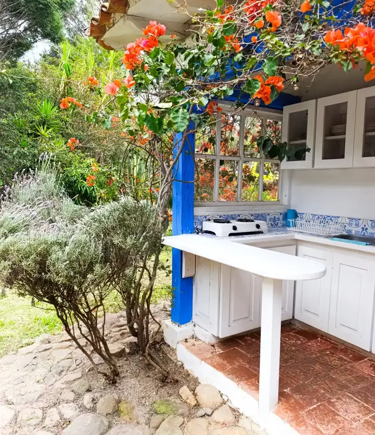 Área de cocina al aire libre en Cabaña el Oteo, Villa de Leyva, rodeada de bougainvillea vibrante.
