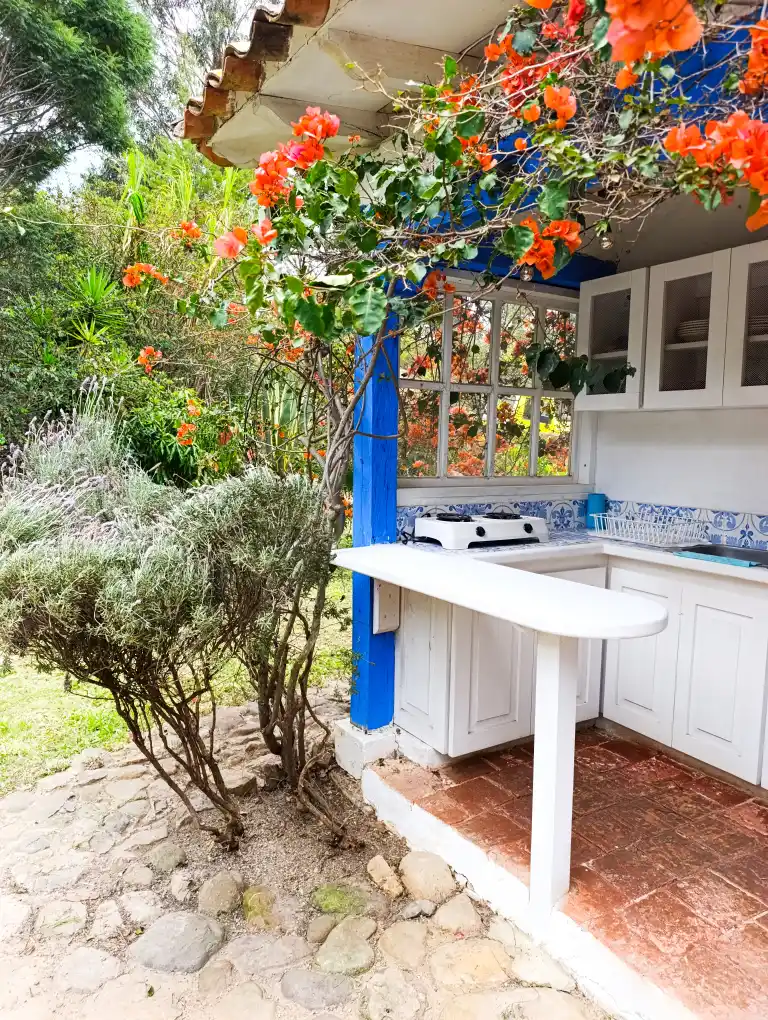 Área de cocina al aire libre en Cabaña el Oteo, Villa de Leyva, rodeada de bougainvillea vibrante.