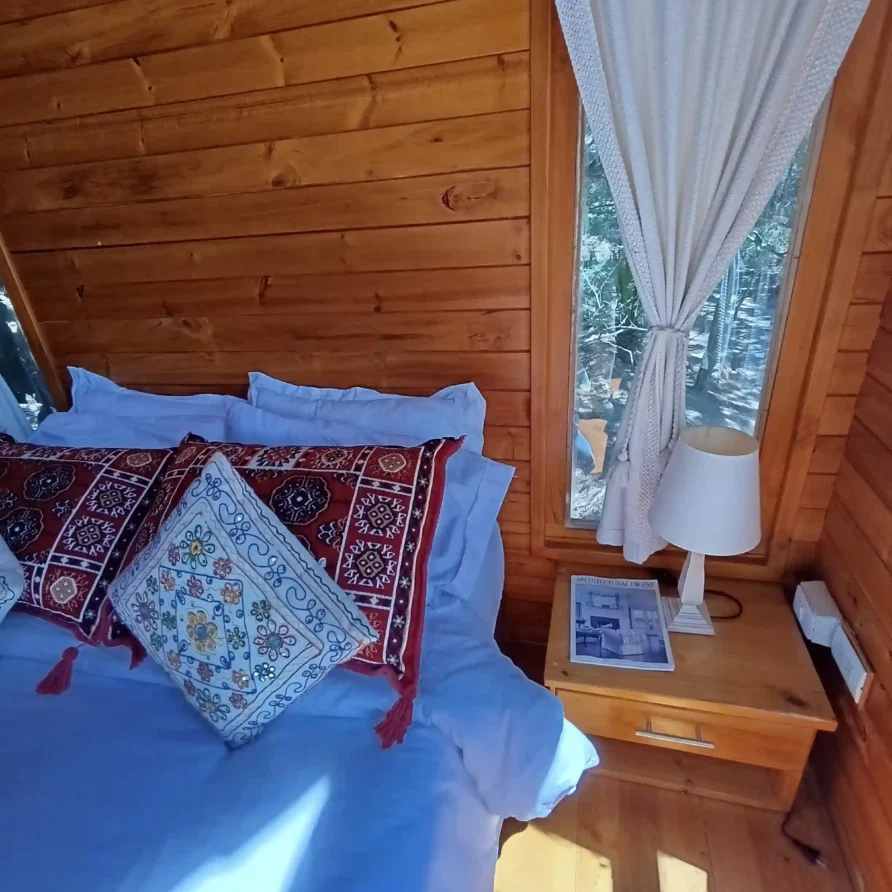 Habitación estilo casa de campo hichatana y zuetana, con mobiliario de pino, textiles decorativos y vistas al exterior. Cabaña el ensueño