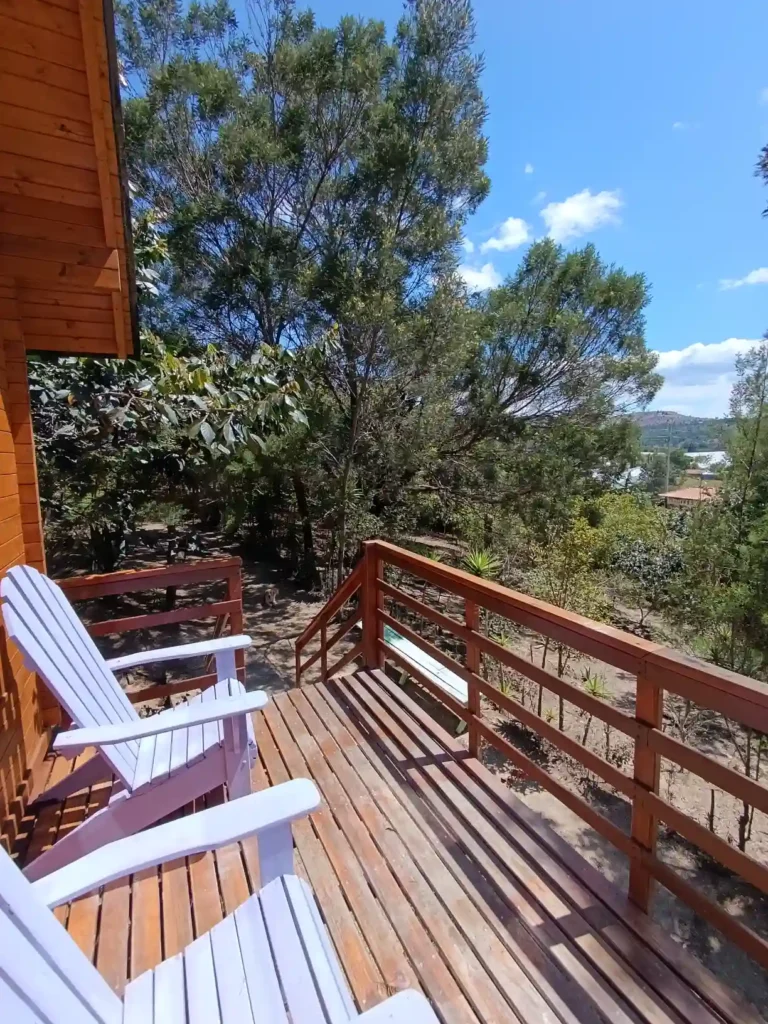 Deck de madera con sillas blancas Adirondack y vista a la naturaleza en Cabaña El Ensueño, ideal para hospedaje en Hichatana y zuetana