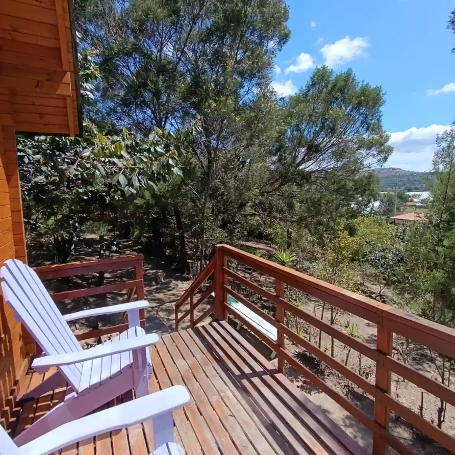 Deck de madera con sillas blancas Adirondack y vista a la naturaleza en Cabaña El Ensueño, ideal para hospedaje en Hichatana y zuetana