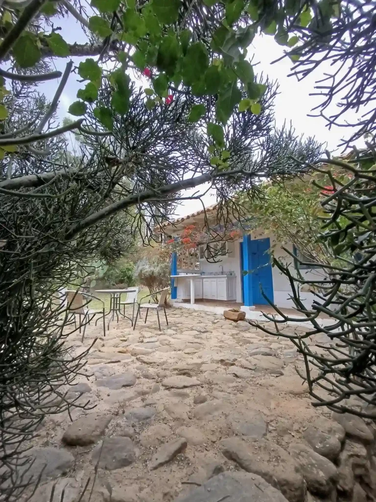 Cabaña El Oteo en Villa de Leyva con patio de piedra, cocina exterior y jardín frondoso. Ideal para hospedaje.