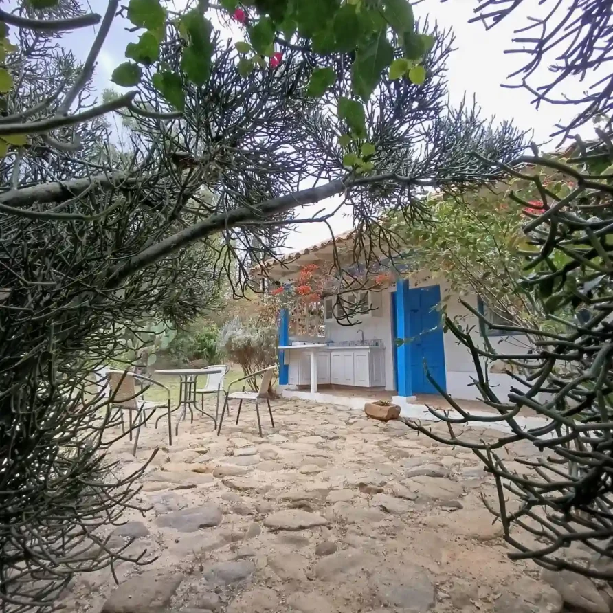 Cabaña El Oteo en Villa de Leyva con patio de piedra, cocina exterior y jardín frondoso. Ideal para hospedaje.