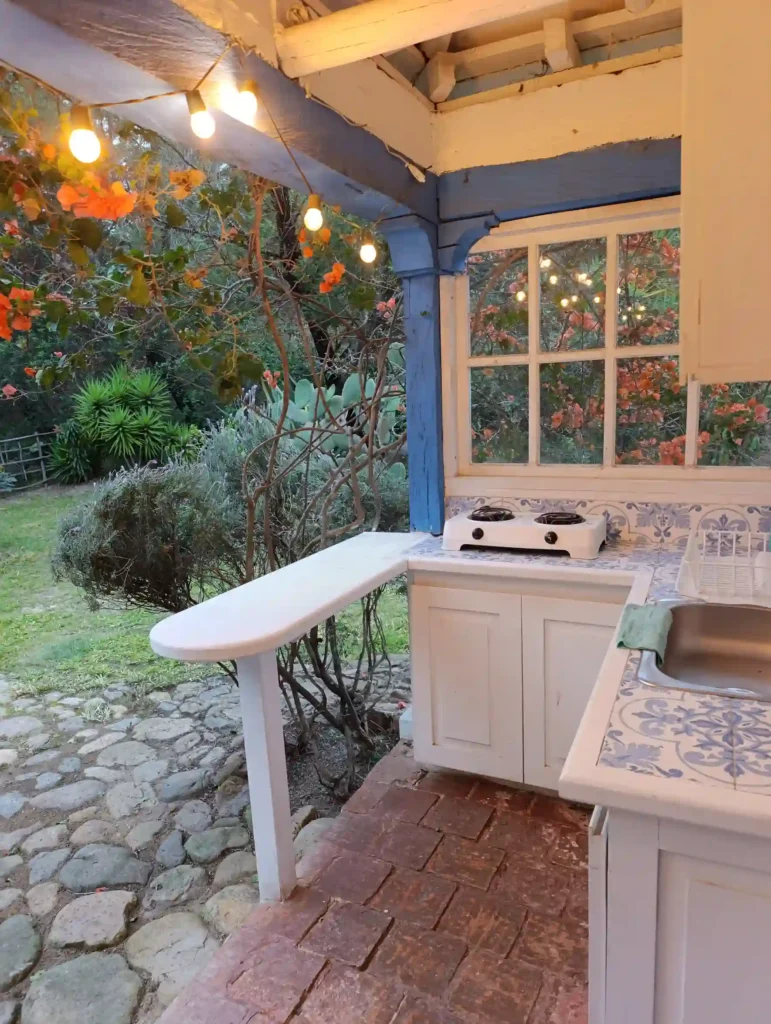 Acogedora cocina al aire libre en casa de campo premium en Villa de Leyva, con fregadero, luces y vegetación.