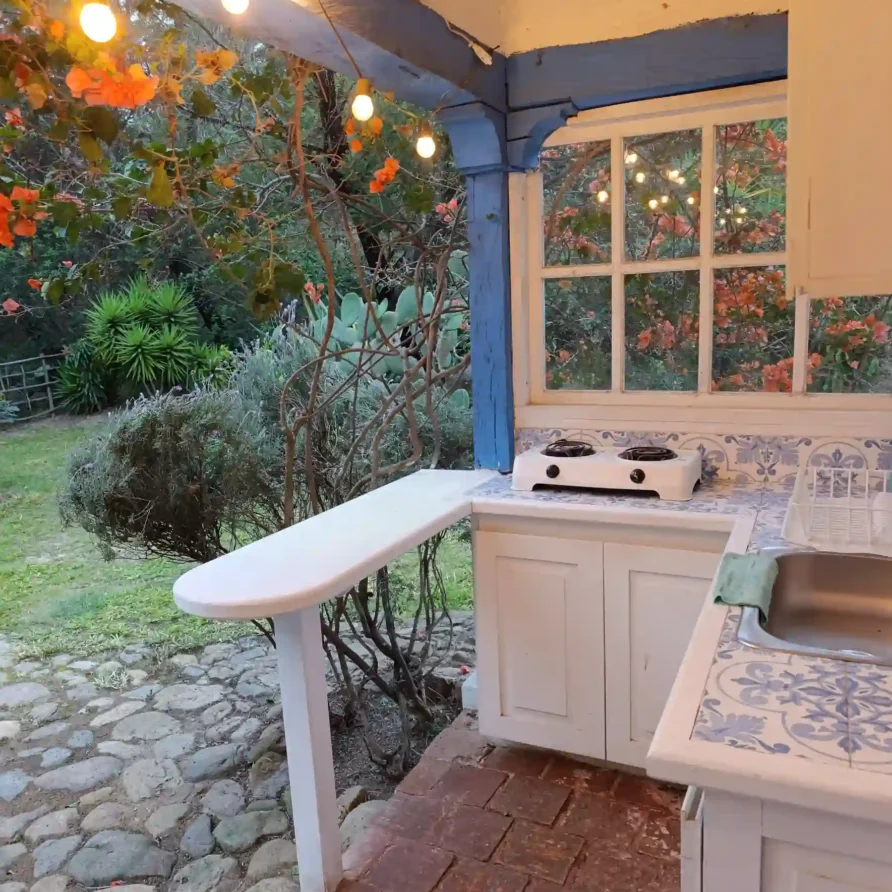 Acogedora cocina al aire libre en casa de campo premium en Villa de Leyva, con fregadero, luces y vegetación.