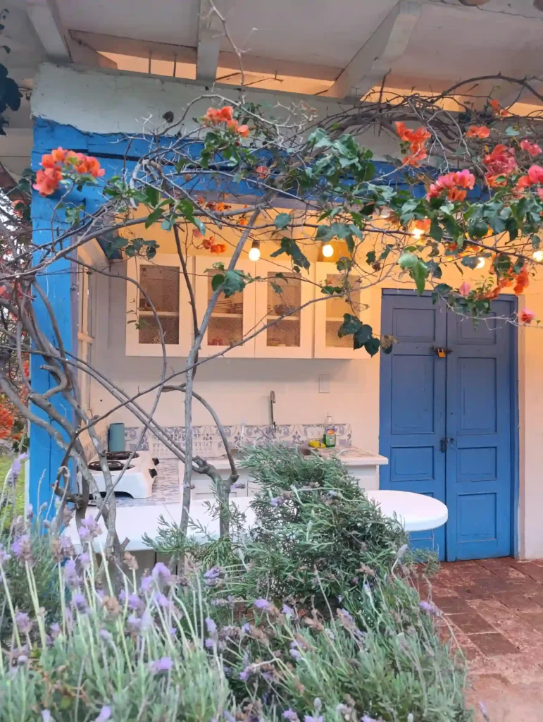 Encantadora cocina exterior de Cabaña El Oteo en Villa de Leyva con flores de buganvilla, luces y detalles azules.