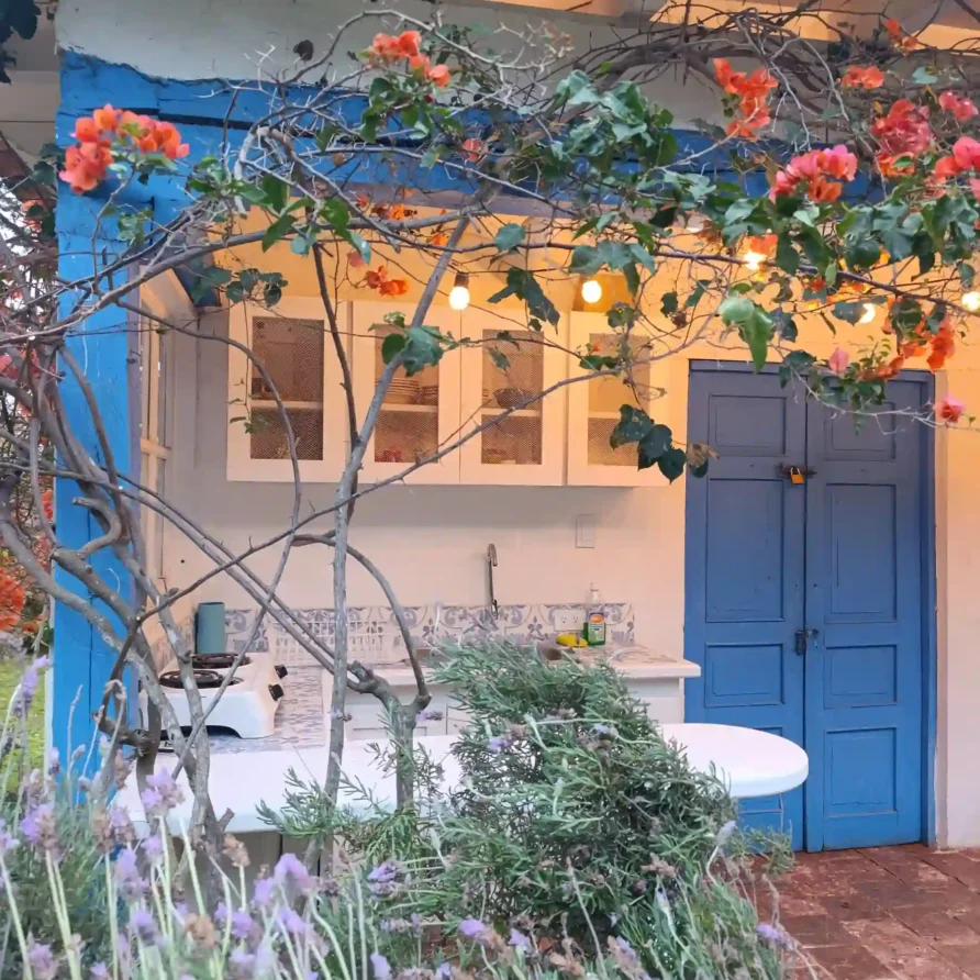 Encantadora cocina exterior de Cabaña El Oteo en Villa de Leyva con flores de buganvilla, luces y detalles azules.