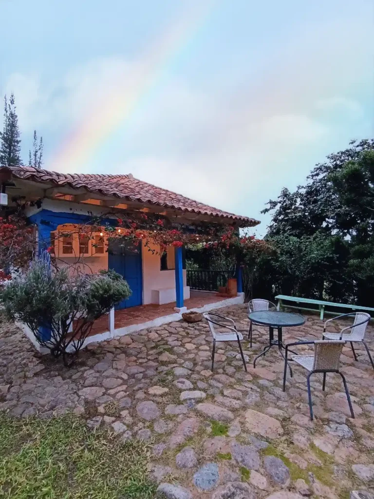Acogedora cabaña El Oteo en Vereda Monquirá, Villa de Leyva, con patio, jardín florido y detalles en azul.