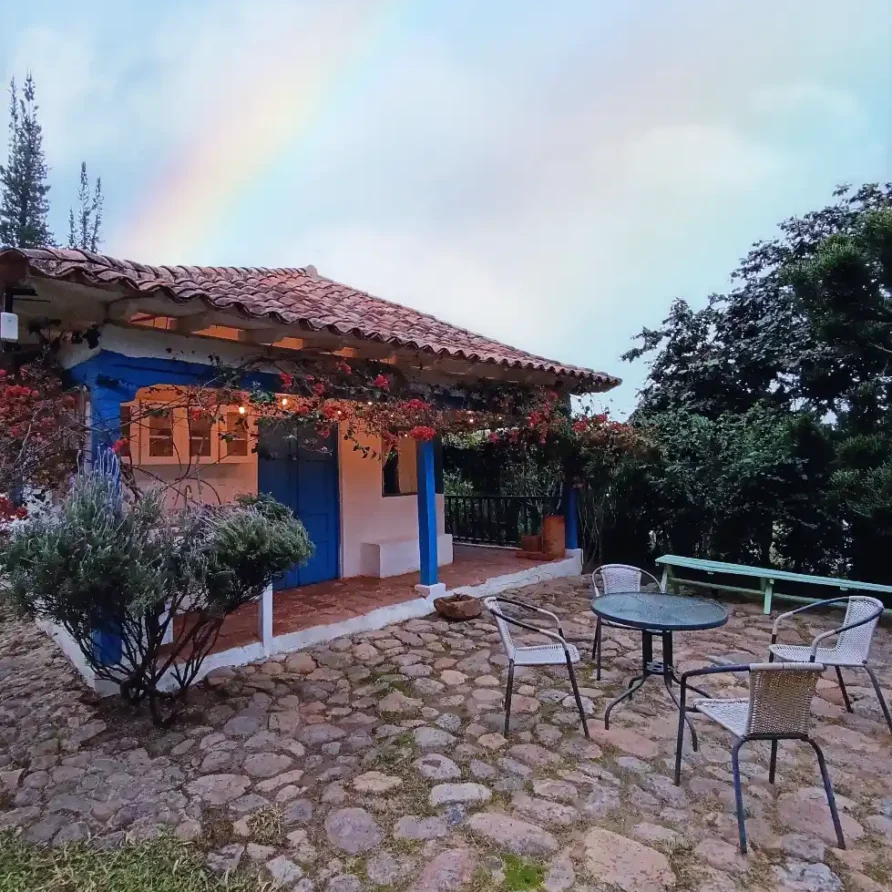 Acogedora cabaña El Oteo en Vereda Monquirá, Villa de Leyva, con patio, jardín florido y detalles en azul.