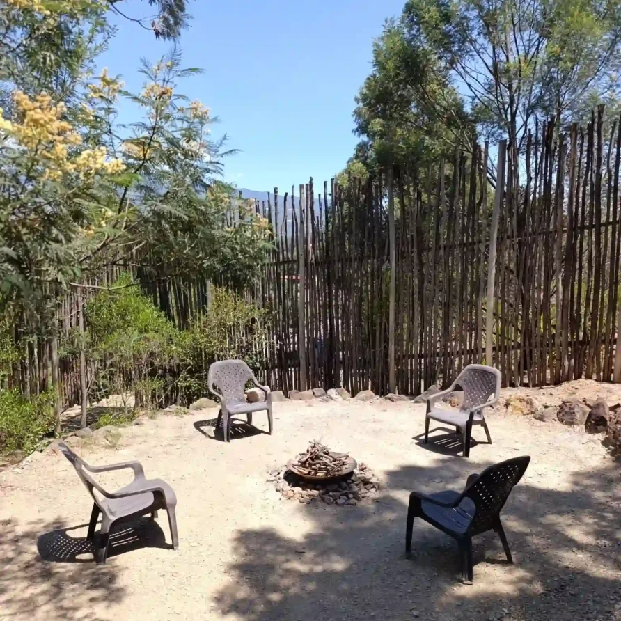 Zona de fogata exterior con cuatro sillas en la Cabaña el Ensueño, Villa de Leyva. Entorno natural y privado para descanso en hotel Hichatana y Zuetana.
